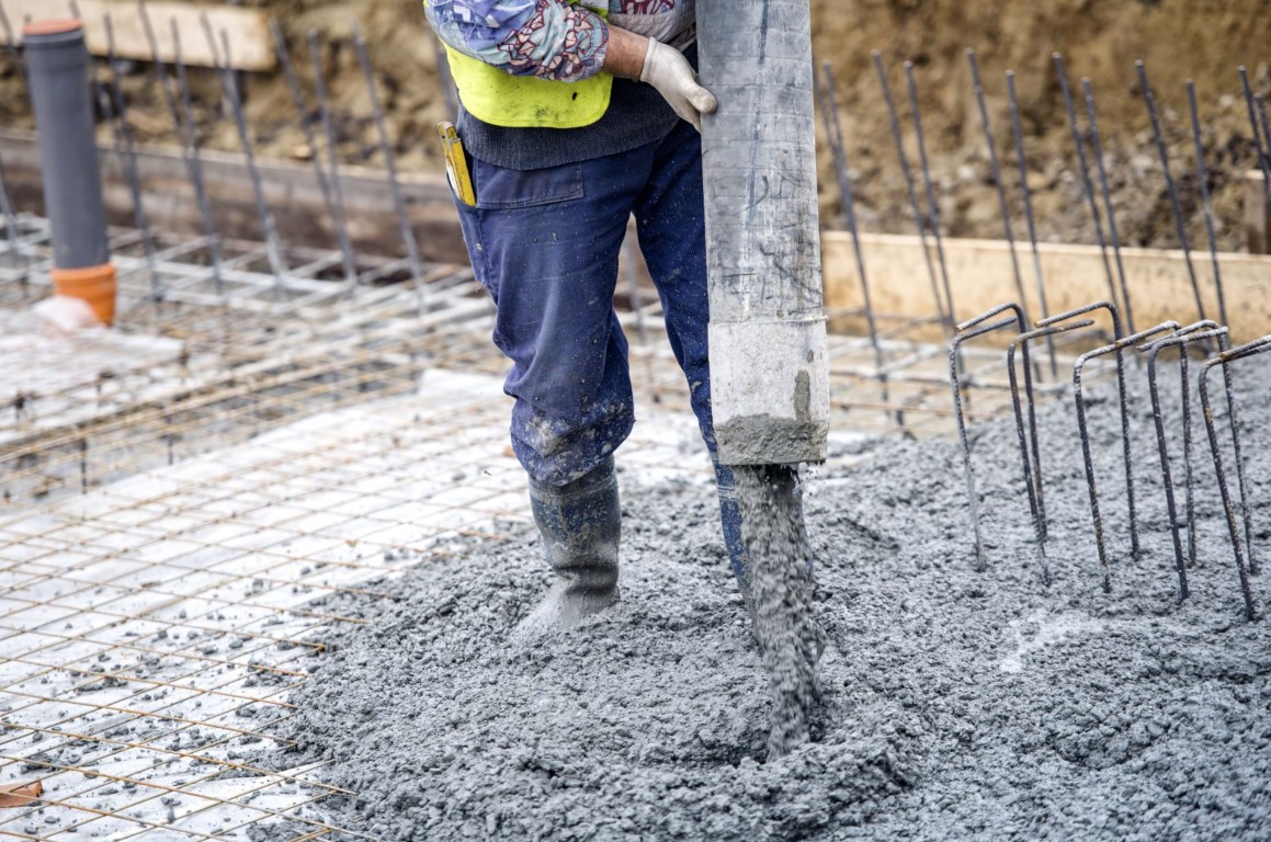 Concrete contractor pouring and spreading a fresh slab on a reinforced construction site in Hayward, CA